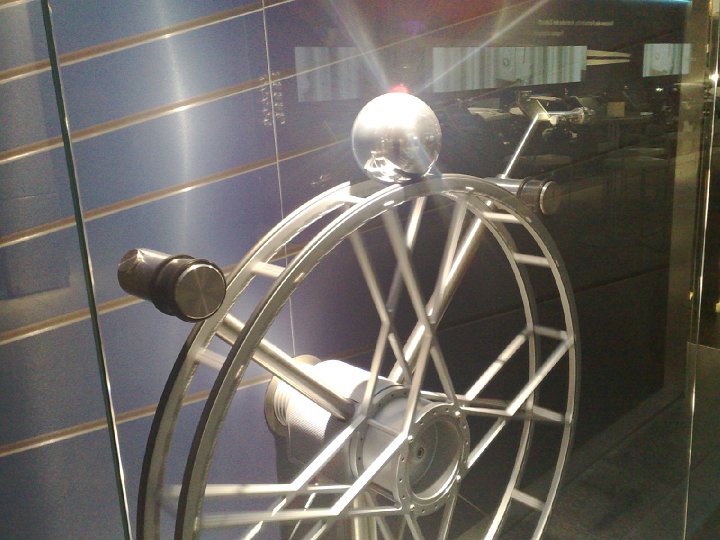 20080918383.jpg - To było prawdziwe cacuszko: komputer (oczywiście z samochodu BMW) na podstawie pomiaru położenia kuli tak sterował ruchami koła, aby utrzymać ją w górnym położeniu. Ale nie to było najbardziej pasjonujące. Mnie zastanawiało co innego: kto i w jaki sposób umieścił tę kulę na górze. Na szczęście po kilku minutach kula wymsknęła się komputerowi spod kontroli i zleciała do lewego zderzaka - miałem więc nadzieję zaraz poznać odpowiedź na to nurtujące mnie pytanie. I rzeczywiście: komputer rozpędził koło w lewo (wprawiając przy tym kulę przy zderzaku w szybki ruch obrotowy w prawo) i chwilę później nagle je przyhamował. Wówczas kula, pod wpływem swojej bezwładności cały czas się kręcąc, sama podjechała w górę. Wtedy koło zaczęło znów się szybko kręcić, aby zatrzymać kulę w tym górnym położeniu i... zabawa zaczęła się od nowa. Genialne!